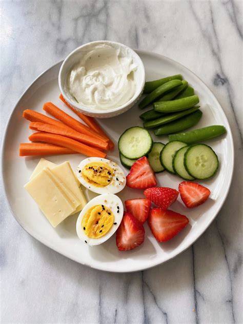 Air-popped popcorn, cucumber slices, and carrot sticks fill a crunchy savory snack plate.