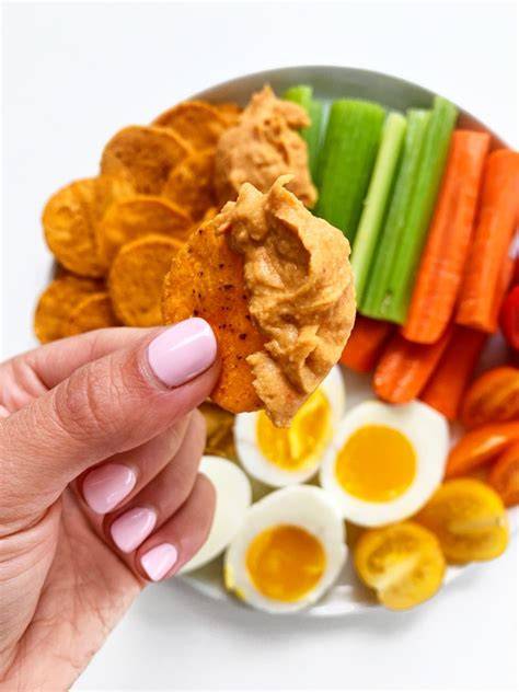 A savory protein snack of sliced boiled egg, cucumber, and cherry tomatoes sits on a small plate.